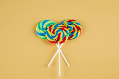 Turuncu arka planda üç renkli lolipop.