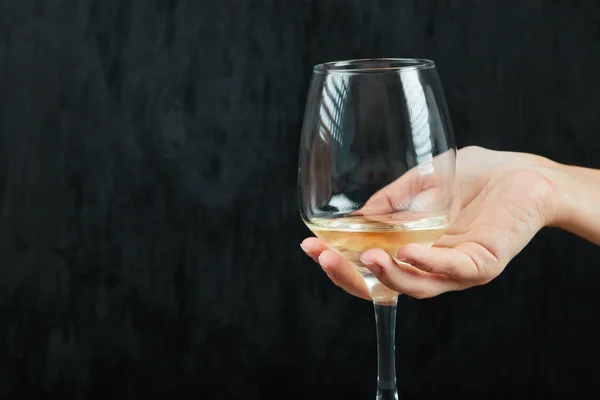 Sosteniendo una copa de vino blanco sobre fondo negro — Foto de Stock
