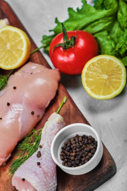 Çiğ tavuk fileto ve taze sebzeli ahşap tabakta bacaklar. Kapat.