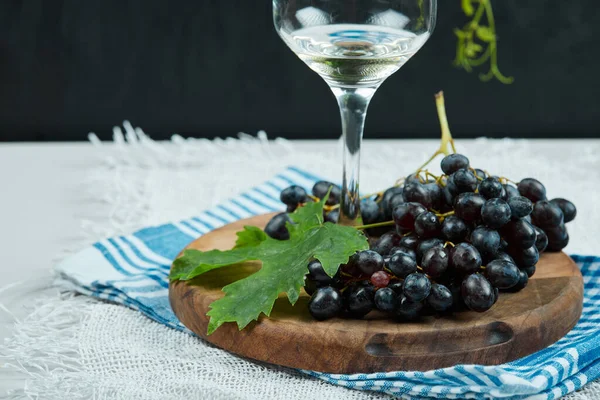 Бокал белого вина с кучей красного винограда вокруг — стоковое фото