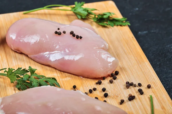 Syrové kuřecí filety na dřevěné desce se zeleninou a pepřovými zrny — Stock fotografie