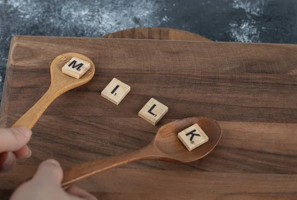Hände mit Kochlöffel aus Holzbuchstaben auf Holzbrett — Stockfoto