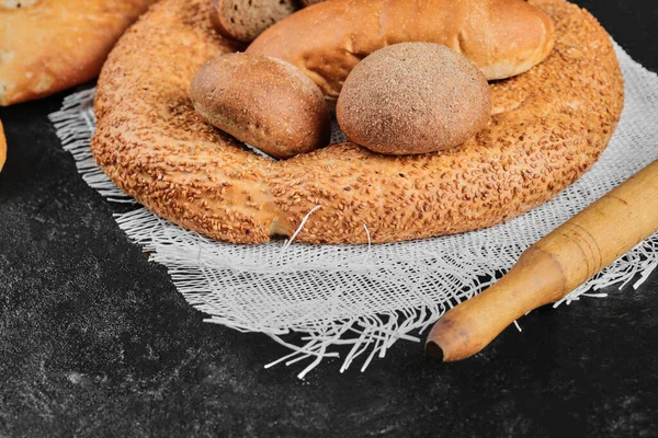 Vários tipos de pão na mesa escura com tigela de farinha — Fotografia de Stock