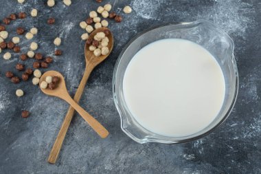 Mermer zemin üzerinde bir kase süt ve mısır gevreği.