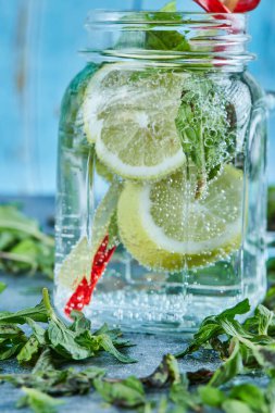 Limonlu mojito kokteyli ve taze nane yapraklı mavi masada nane şekeri.