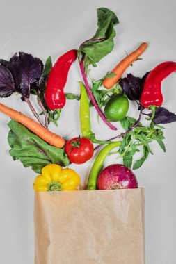 Taze sebzeler, havuçlar, biberler, yeşiller, havuçlar, kağıt torbada soğan.