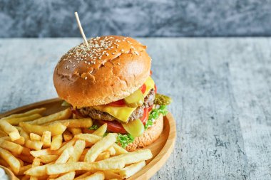 Büyük hamburger ve patates kızartması mermer arka planda ahşap tabakta