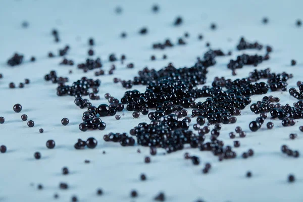 Caviar negro esparcido en la mesa azul —  Fotos de Stock