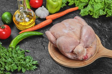 Çiğ tavuk, marul, biber, baharat ve domatesli ahşap tabakta.