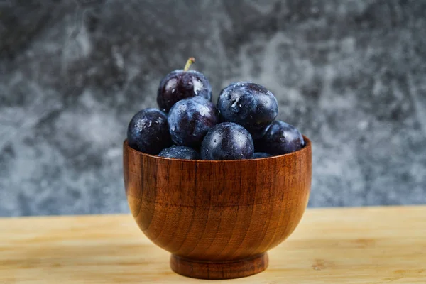 Prunes de jardin dans un bol sur une table en bois — Photo