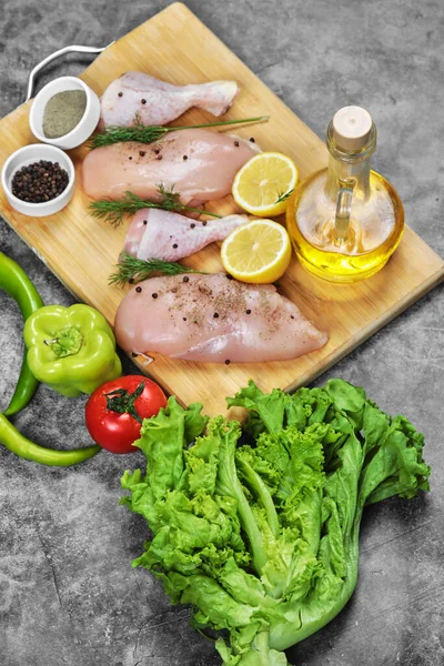 用新鲜蔬菜、香料和油把鸡片和鸡腿放在木制盘子里 — 图库照片