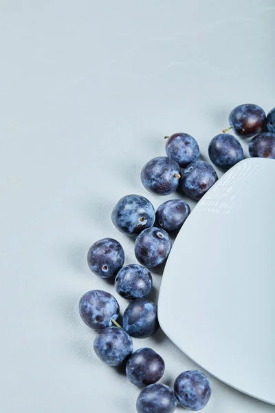 Groupe de prunes fraîches autour de la plaque blanche — Photo