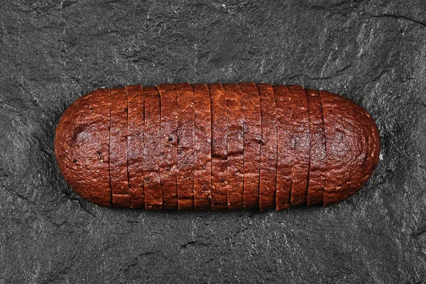 Skivad svart bröd på mörk bakgrund — Stockfoto