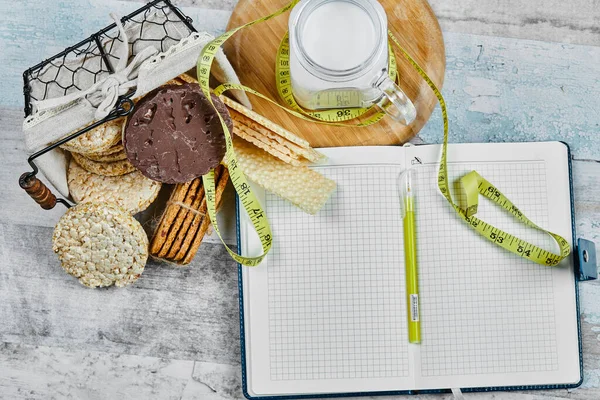 Egy kosár keksz és egy üveg tej egy márványasztalon, jegyzetfüzettel és tollal. — Stock Fotó