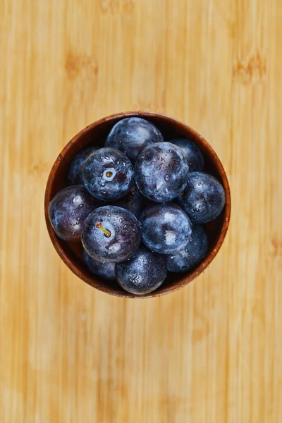 Prunes de jardin dans un bol sur fond en bois — Photo