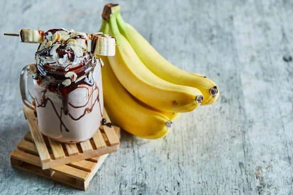 Chocolate smoothie with choco syrup and branch of bananas — Stock Photo, Image