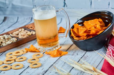 Mavi masada çeşitli atıştırmalıklar, cipsler ve bira var. Arkadaş grubu için tablo