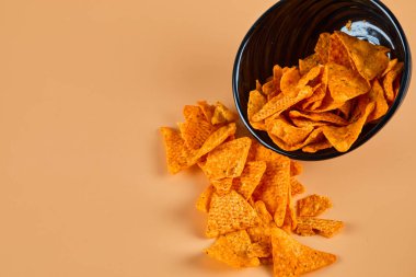 Turuncu arka planda bir kase cips.