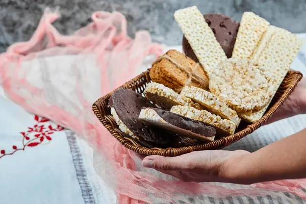 Mano sosteniendo una cesta de galletas mixtas sobre un fondo de mármol —  Fotos de Stock