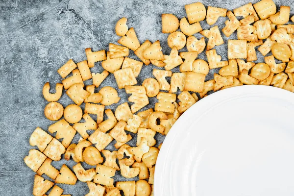 Verspreid alfabet crackers rond een lege plaat op een marmeren achtergrond — Stockfoto