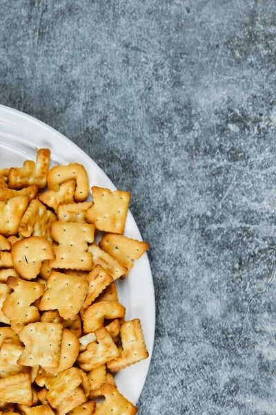 A plate of alphabet crackers on a marble background — Stock Photo, Image