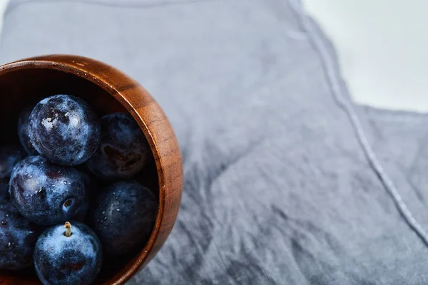Prunes de jardin dans un bol sur nappe grise — Photo