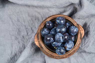 Bahçe erikleri gri masa örtüsünde bir kasede