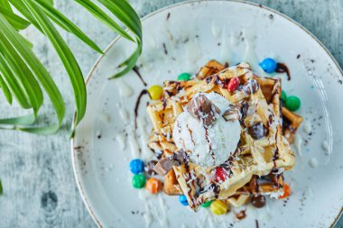 Dondurmalı waffle, şeker, arka planda beyaz tabakta çikolata.