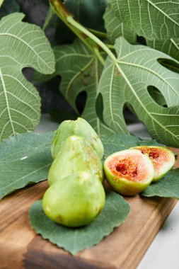 Tahtadaki yeşil incirler yapraklarla çevrili.