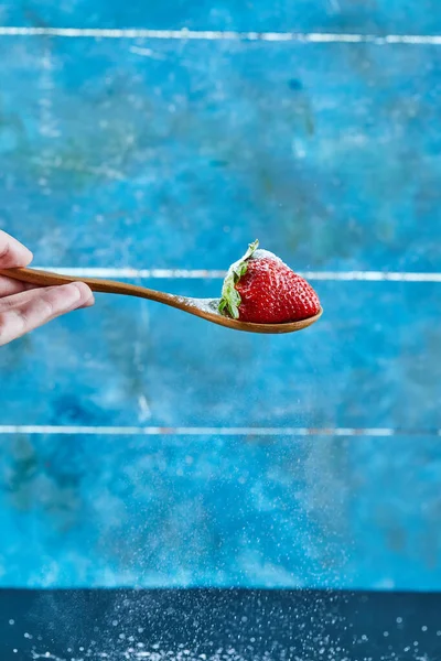 Frau hält Löffel Erdbeere auf blauem Hintergrund — Stockfoto