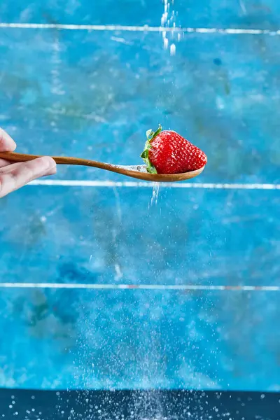 Frau hält Löffel Erdbeere auf blauem Hintergrund — Stockfoto