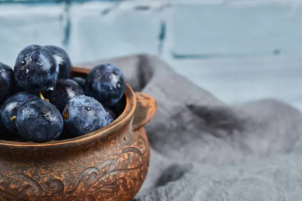 Prunes de jardin dans un bol sur nappe grise — Photo