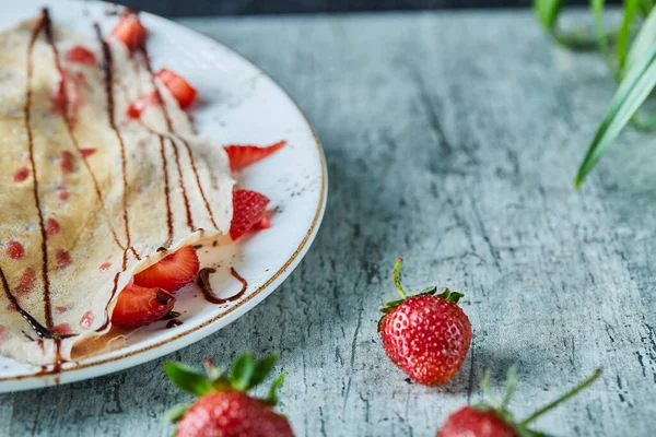 Panquecas com sorvete, morangos e chocolate no prato branco — Fotografia de Stock