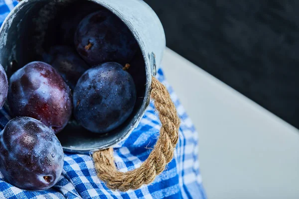 Petit seau de prunes de jardin sur fond sombre avec nappe — Photo