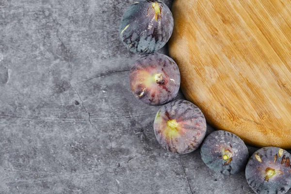 Figues violettes autour d'une assiette en bois sur un fond de marbre — Photo