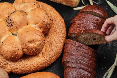 Bir kadın siyah ekmeği çeşitli ekmeklerle birlikte masasında alıyor.