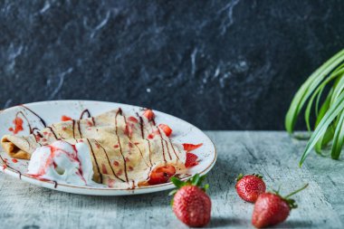 Dondurmalı krep, beyaz tabakta çilek ve çikolata.