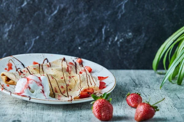 Dondurmalı krep, beyaz tabakta çilek ve çikolata.