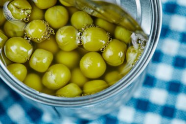 Mavi masa örtüsünde haşlanmış yeşil bezelye konservesi.