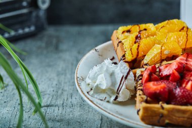 Dondurmalı waffle, muzlu, çilekli, mermer kaplamalı beyaz tabakta çikolata.