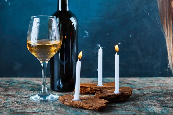 Kaarsen branden met een glas witte wijn en een fles op marmeren tafel — Stockfoto