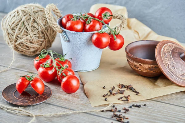 Eimer mit Tomaten und halb geschnittenen Tomaten auf Holztisch — Stockfoto