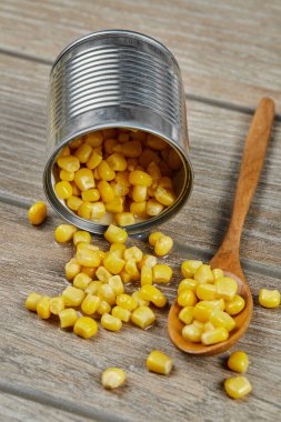 Tahta bir masada kaşıkla haşlanmış mısır konservesi.