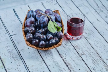 Bahçe erikleri mavi arka planda bir sepet meyve suyu ile