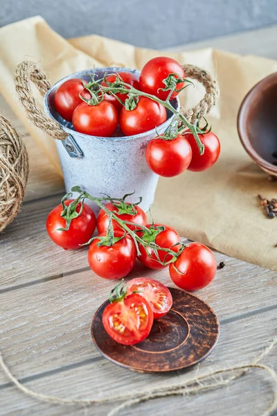 Eimer mit Tomaten und halb geschnittenen Tomaten auf Holztisch — Stockfoto