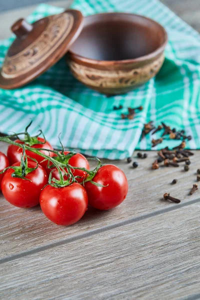 Tomatenbündel mit Zweig und leere Schüssel mit Nelken auf Holztisch — Stockfoto