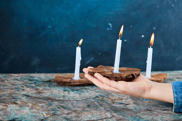 Mujer sosteniendo velas encendidas en mesa de mármol —  Fotos de Stock