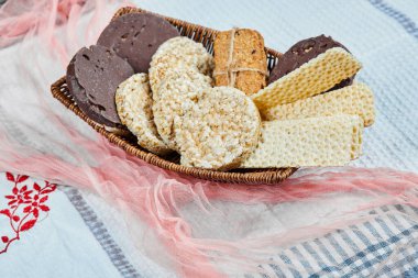 Masa örtüsünün üzerinde bir sepet dolusu bisküvi. Kapat.