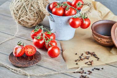 Tahta masada bir kova domates ve yarısı kesilmiş domates.