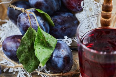 Bahçe erikleri sepetin içinde ve bir bardak meyve suyu ahşap bir masada, yakın